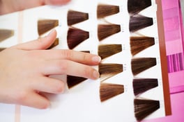 Closeup of clients hand choosing color from hair samples in salon