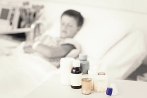 Focus on medicines on table with sick boy in hospital bed